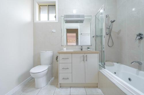 y baño con aseo, lavabo y ducha. en Nunawading Beautiful 3br Housedeckingcourtyard, en Nunawading