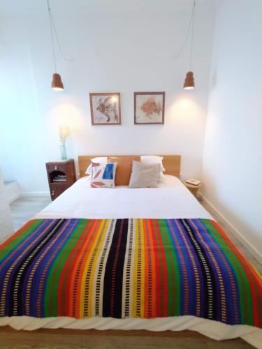 1 dormitorio con una manta de rayas de colores en una cama en MAJU Concept House - Beja Centro Histórico, en Beja