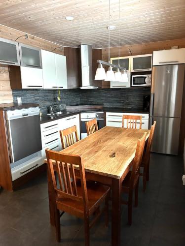 a kitchen with a wooden table with chairs and a refrigerator at Hietavilla Borealis in Ruka