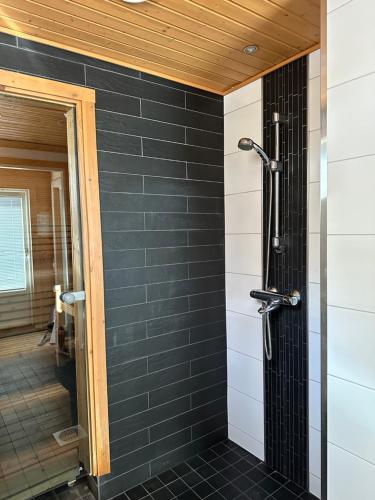a shower in a bathroom with black tiles at Hietavilla Borealis in Ruka