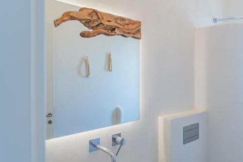 a bathroom with a mirror and a wooden carving on the wall at Aegean Feelings in Piso Livadi