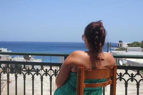 a woman sitting in a chair looking at the ocean at Nikos Hotel in Diafani