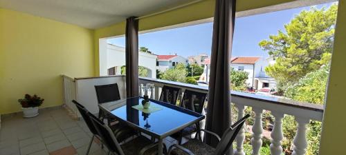 a balcony with a table and chairs and a large window at Apartments Bresina in Povljana