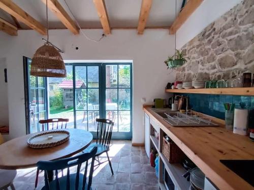 a kitchen with a table and chairs and a stone wall at ZebRegény Vendégház in Zebegény