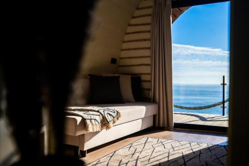 a bedroom with a bed and a view of the ocean at Glamping Maracujá - Oasis Paradise in Ribeira Brava