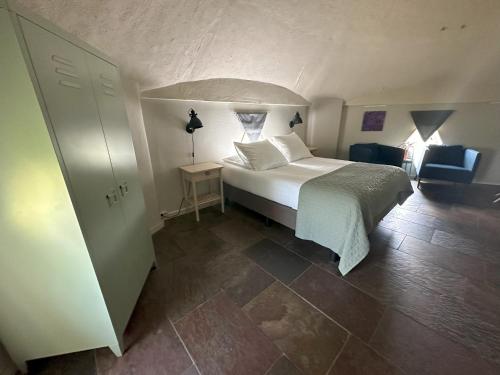 a bedroom with a white bed and a blue chair at Hotel de Watertoren in Dordrecht