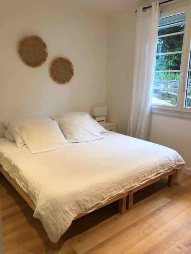- un lit blanc dans une chambre avec fenêtre dans l'établissement Jolie Maison à 5mins des plages et du lac, à Soorts-Hossegor
