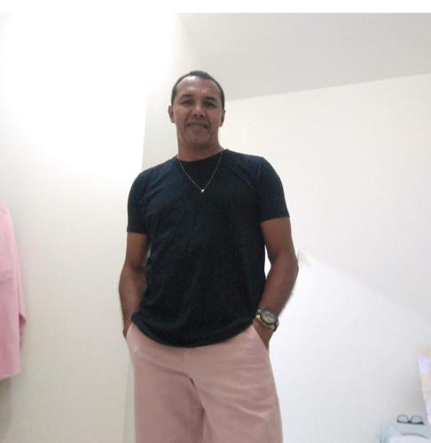 a man in a black shirt standing in a room at Casa aconchegante in Caraguatatuba