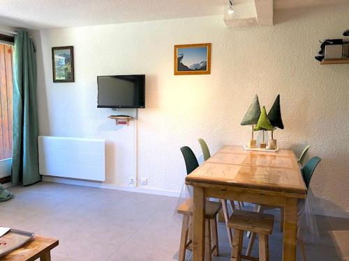 une salle à manger avec une table avec des chaises et une télévision dans l'établissement LES SAPINS Joséphine Immobilier, à Saint-Chaffrey