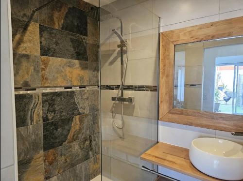 a bathroom with a shower and a sink and a mirror at Un petit coin de paradis à La Réunion in Saint-Joseph