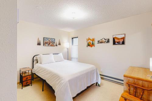 Schlafzimmer mit einem Bett mit weißer Bettwäsche und Bildern an der Wand in der Unterkunft Shimmering Summit Hideaway in Mount Crested Butte