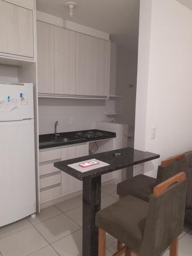a kitchen with a table and a white refrigerator at APARTAMENTO PARA FERIAS BLUMENAU in Blumenau