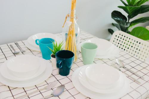 einen Tisch mit weißen Platten, blauen Tassen und Pflanzen in der Unterkunft -Lake View- Mount Austin IKEA Toppen 5 mins - B113 in Johor Bahru