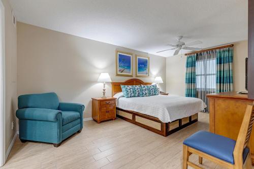 a bedroom with a bed and a blue chair at The Resort on Cocoa Beach, a VRI resort in Cocoa Beach