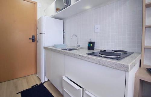 a kitchen with a counter with a sink and a refrigerator at Refúgio acolhedor Praia e comércio à porta in Salvador