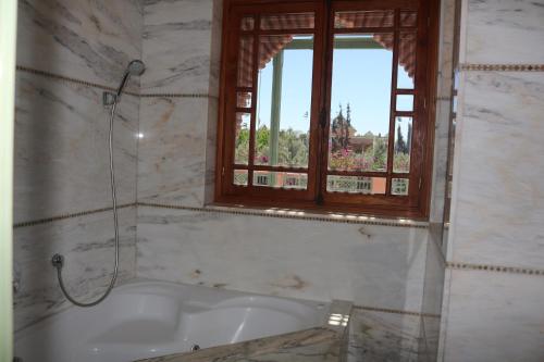 La salle de bains est pourvue d'une baignoire et d'une fenêtre. dans l'établissement nakhil villa palm, à Marrakech