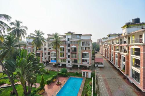 an apartment complex with a swimming pool and palm trees at Amazing Pool View Candolim Goa 1BHK Apartment in Candolim