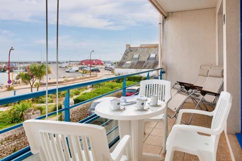 d'un balcon avec une table et des chaises offrant une vue sur la rue. dans l'établissement À 200m de la plage, appartement vue mer pour 2, à Plobannalec-Lesconil