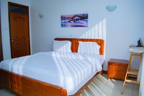 Schlafzimmer mit einem Holzbett mit weißer Bettwäsche in der Unterkunft Kilimani Extended Stays in Nairobi