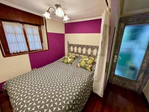 a bedroom with a bed with purple walls and a window at Utsa Eski -Piso con encanto en 1ª linea de puerto in Bermeo