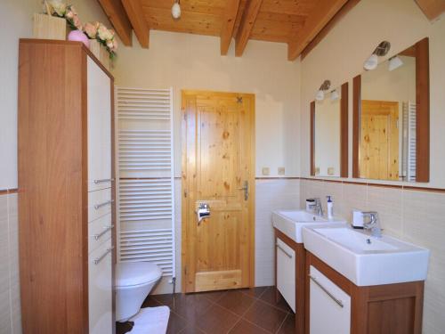 La salle de bains est pourvue de 2 lavabos, de toilettes et d'une porte en bois. dans l'établissement Zrubová chata Tatry, à Stará Lesná