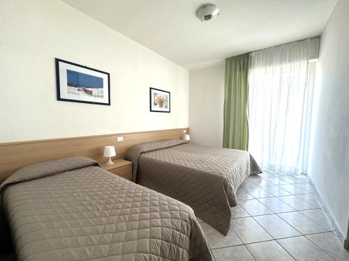 een hotelkamer met twee bedden en een raam bij Laguna Grande - Appartamenti in Bibione