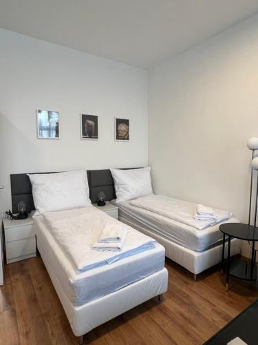 2 letti in una camera con pareti bianche e pavimenti in legno di Harmony Apartment at U6-Metro Vienna a Vienna