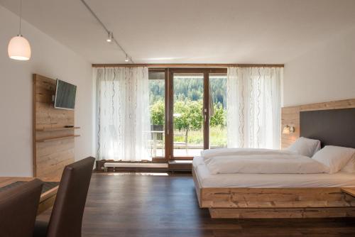 a bedroom with a bed and a large window at Ferienpark Tulai - Fam. Carl in Scuol