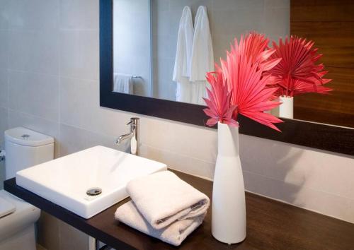a bathroom with a sink and a vase with red flowers at Villa Perla in Puerto del Carmen
