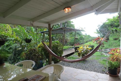 a hammock on a porch with a view of a garden at Apartamento Karibu in Manuel Antonio