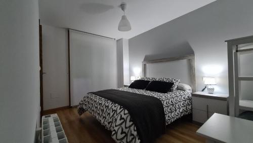 1 dormitorio con 1 cama con edredón blanco y negro en Piso puerto Foz, en Foz