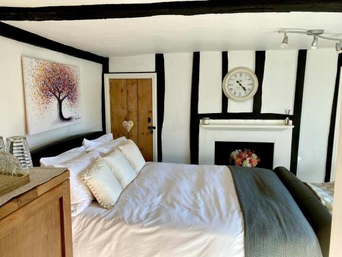 a bedroom with a bed with a clock on the wall at Chestnut Tree Cottage, 7 High Street in Ardingly