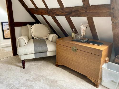 a room with a chair and a wooden dresser at Chestnut Tree Cottage, 7 High Street in Ardingly