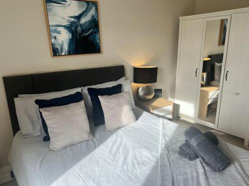 a bedroom with a white bed with pillows and a mirror at Beautiful traditional flat in the center of Largs. in Largs