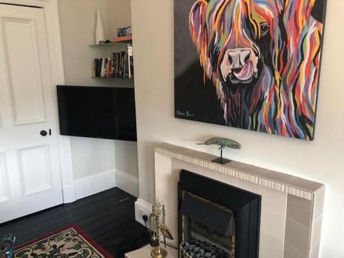 a painting of a dog hanging over a fireplace at Beautiful traditional flat in the center of Largs. in Largs