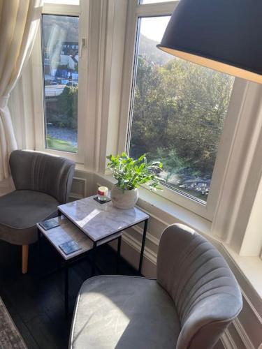 a living room with two chairs and a table and a window at Beautiful traditional flat in the center of Largs. in Largs