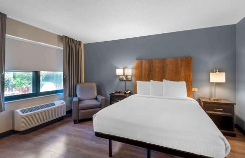 um quarto com uma cama branca e uma cadeira em Extended Stay America Suites - Charlotte - Pineville - Park Rd em Charlotte