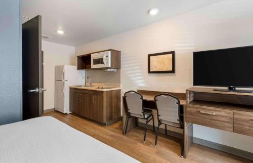 a hotel room with a desk with two chairs and a television at Extended Stay America Suites - Charlotte - Matthews in Charlotte