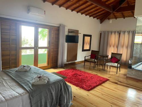 a bedroom with a bed and a table and chairs at Hotel Pousada Bella Locanda in Campos do Jordão
