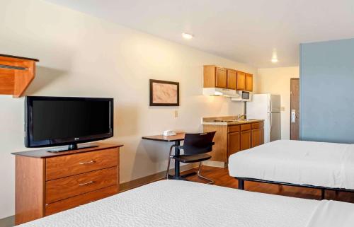 コロラドスプリングスにあるExtended Stay America Select Suites - Colorado Springs - Airportのベッドとテレビが備わる小さなホテルルームです。