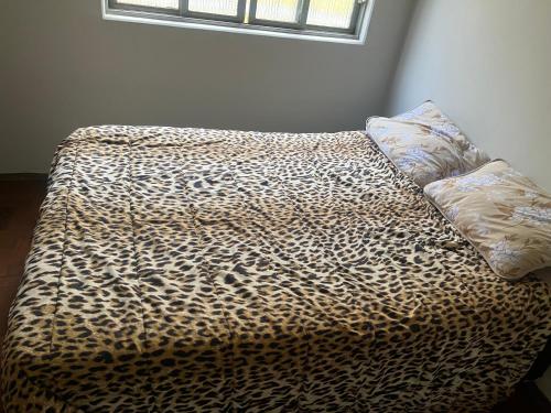 a bed with a leopard print blanket and a pillow at Pousada âncora in Uberlândia