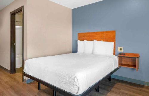 a bedroom with a white bed with a wooden headboard at Extended Stay America Select Suites - Jacksonville - North in Jacksonville