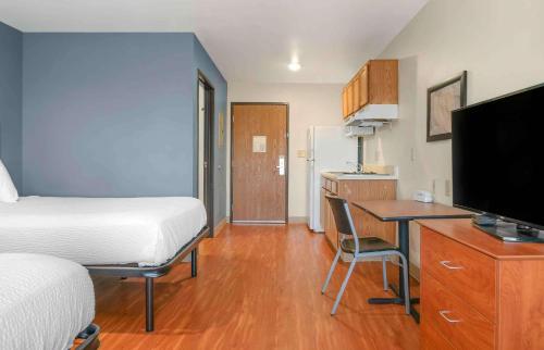 a hotel room with a bed and a desk with a television at Extended Stay America Select Suites - Kalamazoo - West in Kalamazoo