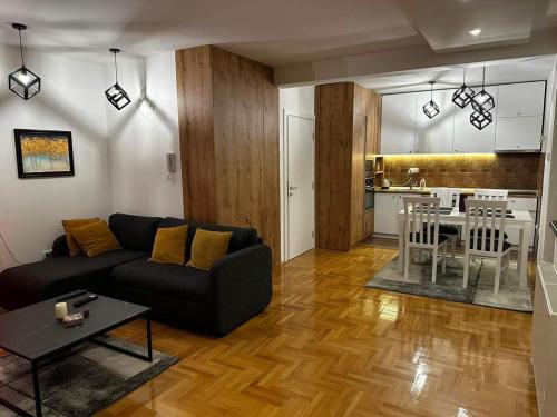 Una sala de estar con un sofá y una mesa y una cocina. en Riverside apartment with private parking, en Niš