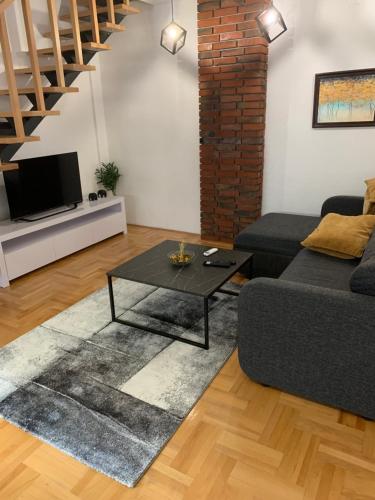 una sala de estar con un sofá y una mesa en Riverside apartment with private parking, en Niš