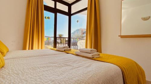 a bedroom with a bed with yellow curtains and a window at Sunny apartment near the beach in Playa del Ingles
