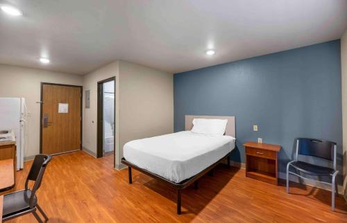 1 dormitorio con cama y pared azul en Extended Stay America Select Suites - Lubbock - South en Lubbock