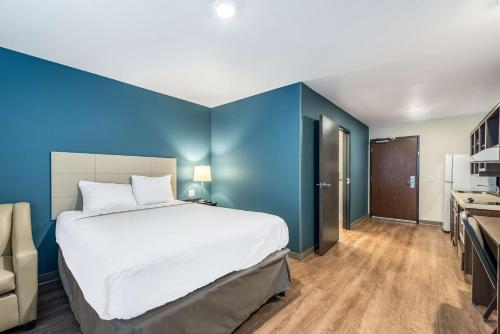 een slaapkamer met een groot bed en een blauwe muur bij Extended Stay America Suites - Minneapolis - Airport - Mendota Heights in Mendota Heights