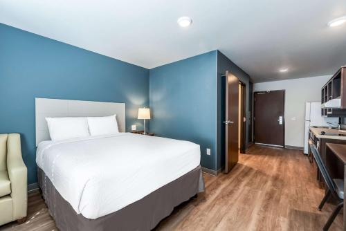 a bedroom with a large bed and a blue wall at Extended Stay America Suites - Minneapolis - Fridley in Fridley