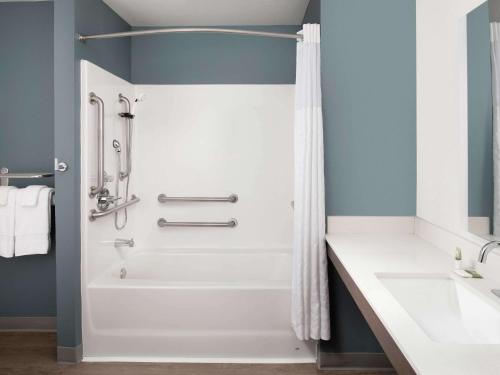 a bathroom with a shower and a white tub at Extended Stay America Suites - Minneapolis - Fridley in Fridley